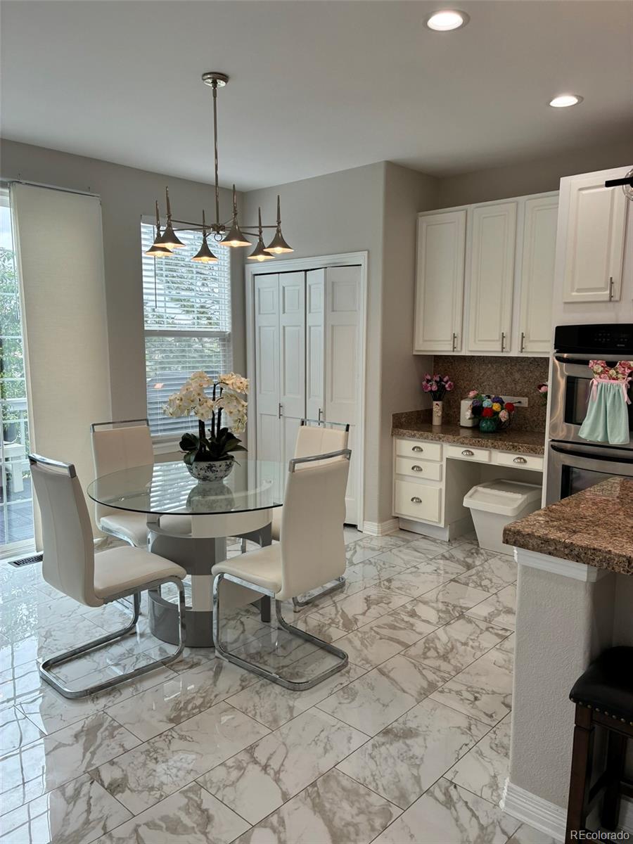 7242 South Rome Street Aurora, CO 80016 - Photo 11 of 33 a kitchen with a dining table chairs and white cabinets