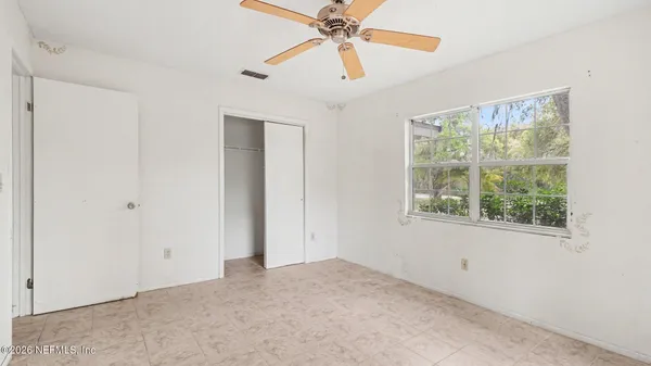 an empty room with a ceiling fan and a window