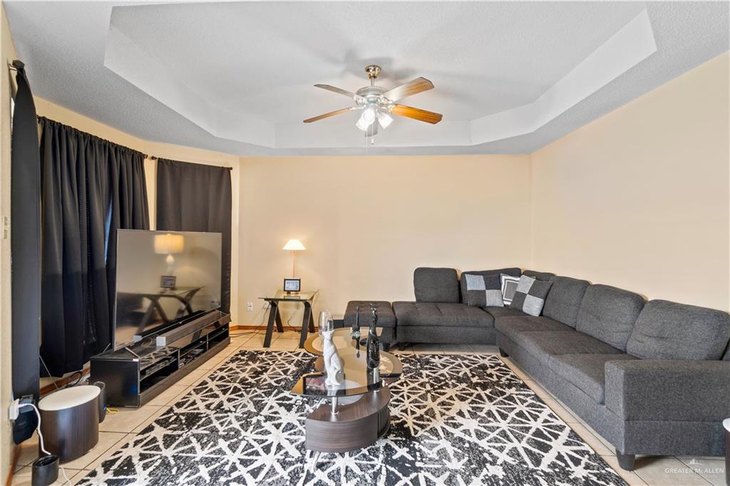 106 Rosa Priego Street Donna, TX 78537 - Photo 3 of 25 Living room featuring light tile patterned floors, a tray ceiling, and ceiling fan