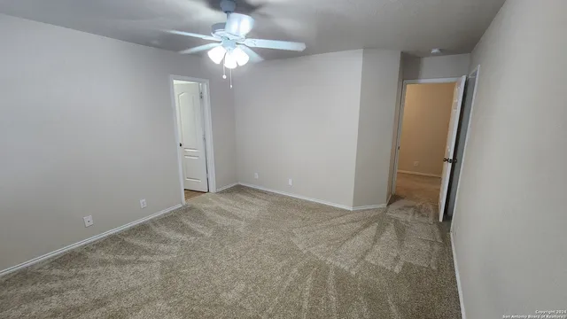 an empty room with a chandelier fan and closet
