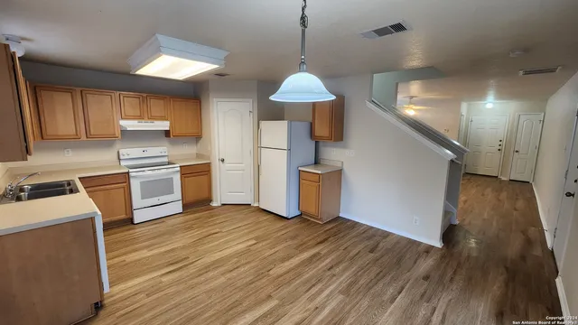 a kitchen with granite countertop a stove a sink and a refrigerator