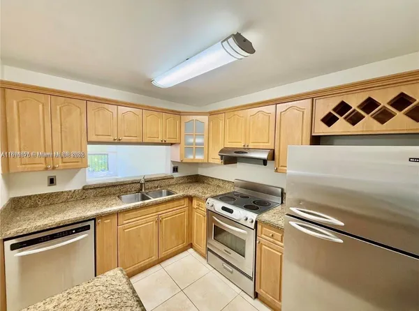 a kitchen with granite countertop a sink a stove a microwave and cabinets