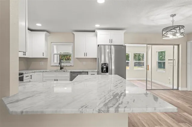 a kitchen with granite countertop white cabinets and stainless steel appliances