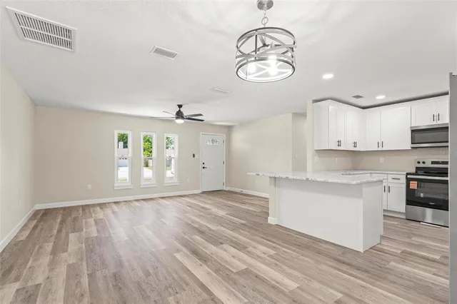 a kitchen with stainless steel appliances granite countertop a refrigerator a stove a sink and a granite counter tops with white cabinets