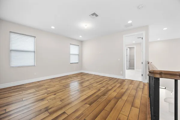 a view of empty room with wooden floor and fan