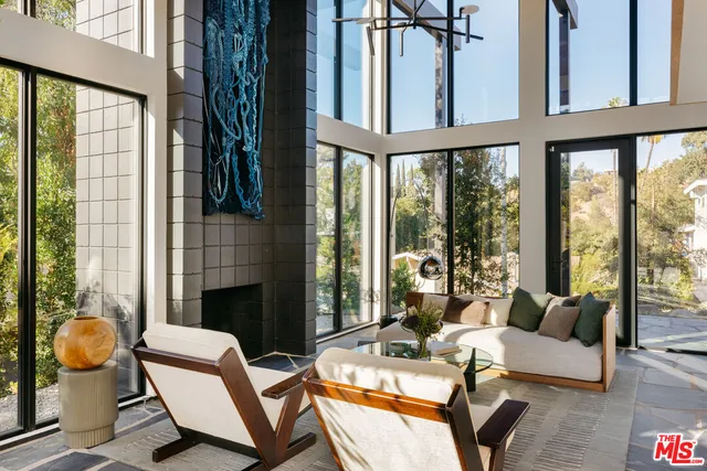 a living room with furniture fireplace and large windows