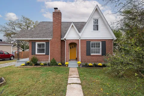 a front view of a house with a yard and potted plants