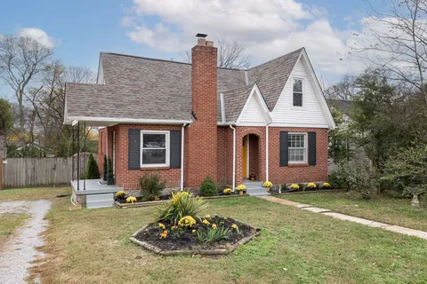 a view of a brick house with a yard potted plants