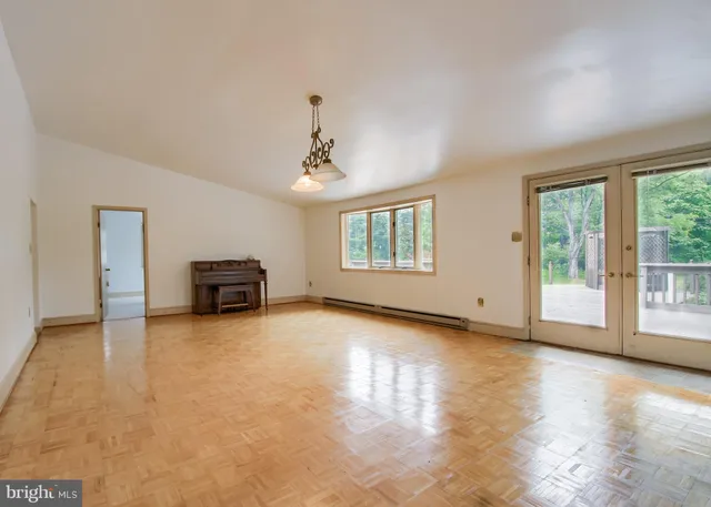 a view of a hallway with wooden floor and a bathroom space