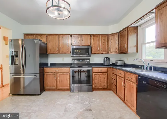 a kitchen with stainless steel appliances granite countertop a stove sink microwave and window