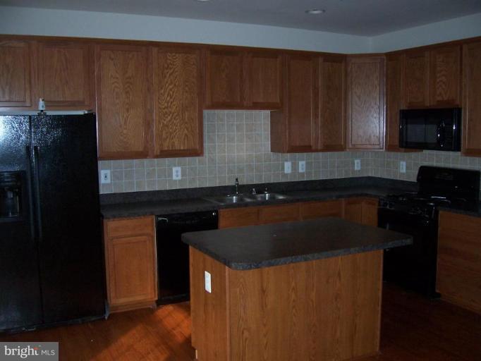 729 Compass Road East Middle River, MD 21220 - Photo 4 of 10 a kitchen with granite countertop wood cabinets and black appliances