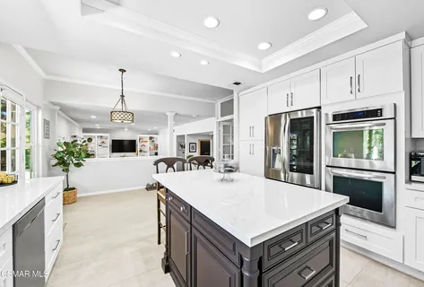 a kitchen with kitchen island a stove a sink a oven and a refrigerator