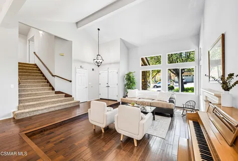 a living room with furniture floor to ceiling window and wooden floor
