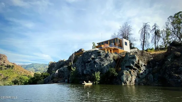a large body of water next to a building with large trees