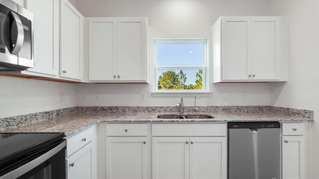 a kitchen with stainless steel appliances granite countertop white cabinets sink and dishwasher