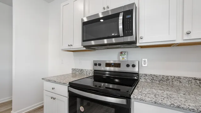 a kitchen with granite countertop white cabinets and stainless steel appliances