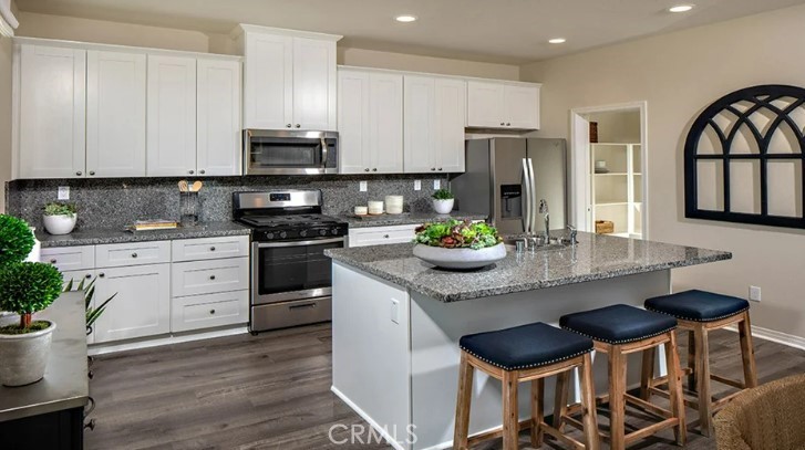 36838 Arietta Way Beaumont, CA 92223 - Photo 4 of 26 a kitchen with stainless steel appliances granite countertop a stove top oven a refrigerator a sink and white cabinets with wooden floor