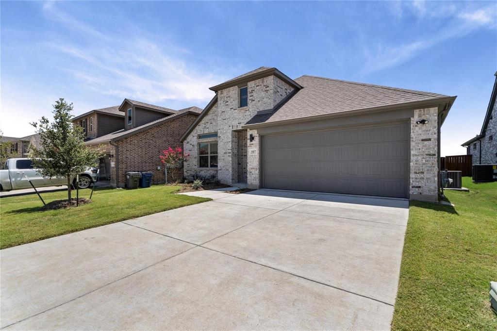 507 Avocet Road Princeton, TX 75407 - Photo 2 of 31 Stone and brick exterior with a gray garage door, concrete driveway, and established landscaping