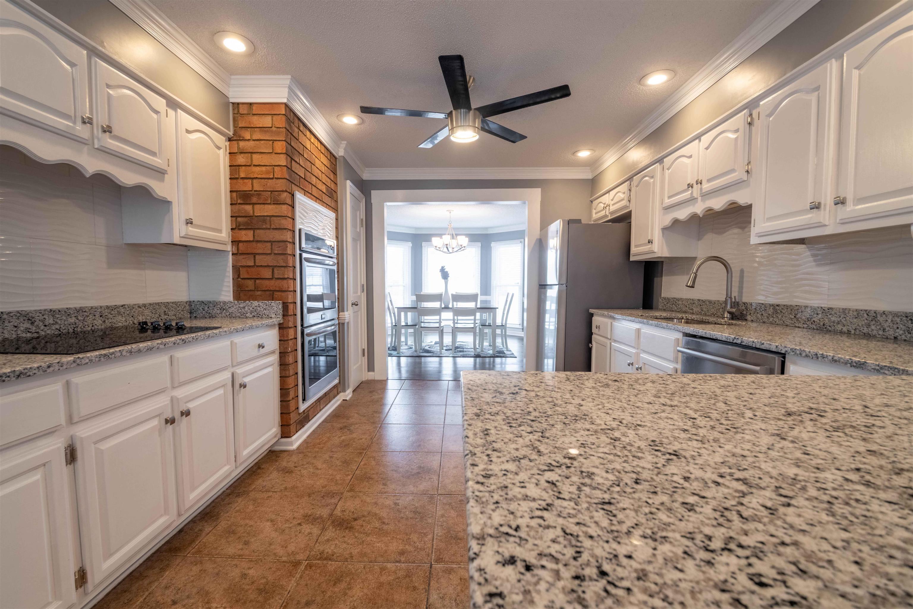 2630 Davies Plantation Road Memphis, TN 38016 - Photo 18 of 37 Kitchen with backsplash, white cabinetry, light stone countertops, a ceiling fan, and crown molding