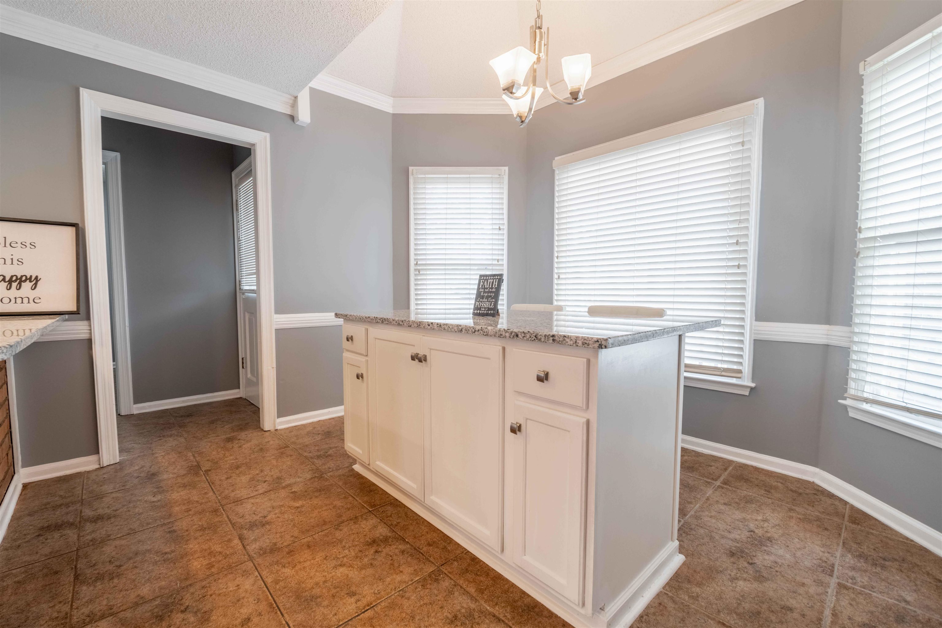 2630 Davies Plantation Road Memphis, TN 38016 - Photo 23 of 37 Kitchen featuring a center island, white cabinetry, crown molding, suspended lighting, and light stone countertops