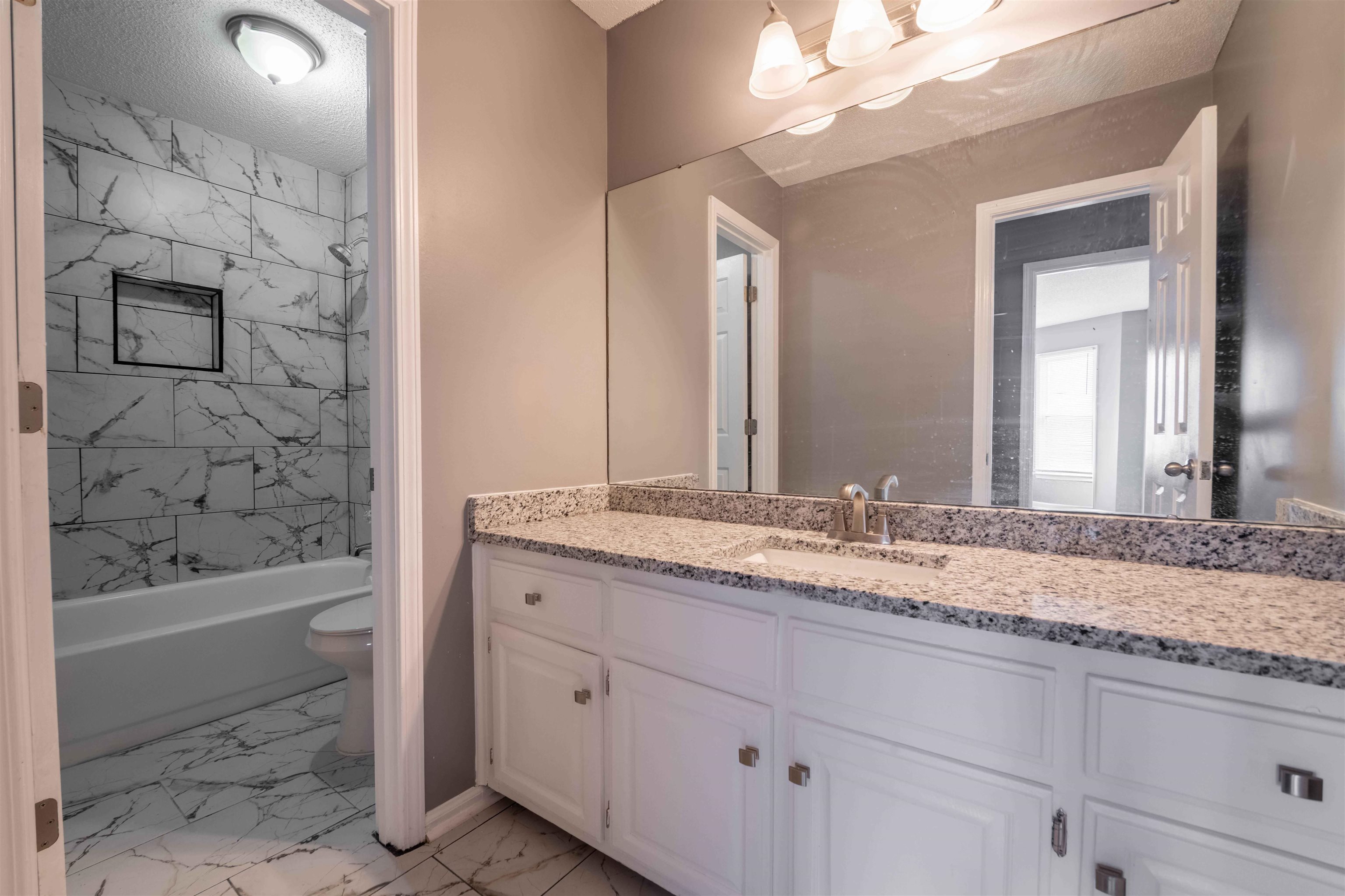 2630 Davies Plantation Road Memphis, TN 38016 - Photo 33 of 37 Full bath featuring light marble finish flooring, vanity, bathing tub / shower combination, and a textured ceiling