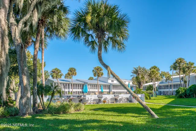 a view of a house with a small yard and palm trees