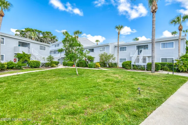 a front view of a house with a yard and potted plants