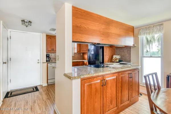 a kitchen with stainless steel appliances granite countertop a refrigerator a stove and a sink with wooden floor
