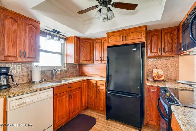 a kitchen with stainless steel appliances granite countertop a refrigerator a sink dishwasher a stove and white countertops with wooden floor