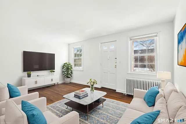 a living room with furniture a flat screen tv and a window