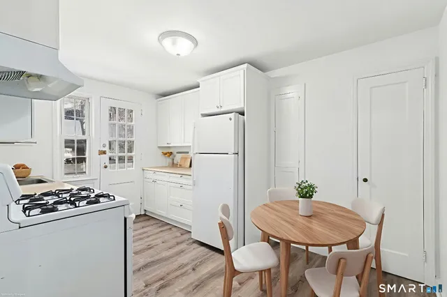 a kitchen with stainless steel appliances a refrigerator a stove a dining table and chairs