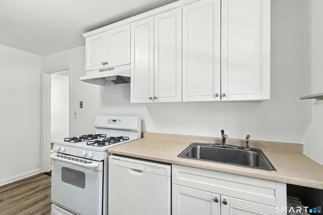 a kitchen with granite countertop white cabinets and white appliances