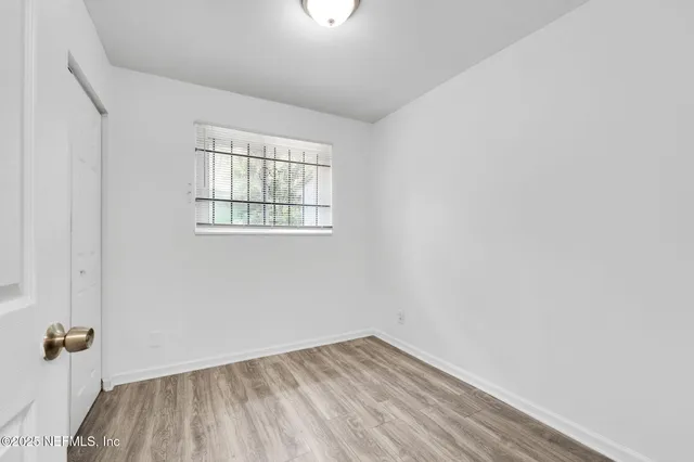a view of empty room with wooden floor and window