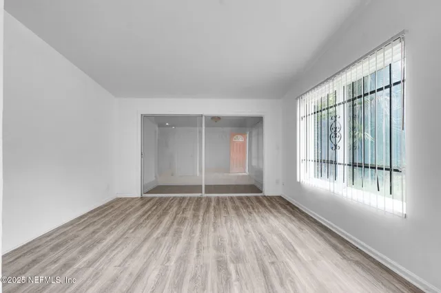 a view of an empty room with wooden floor and a window