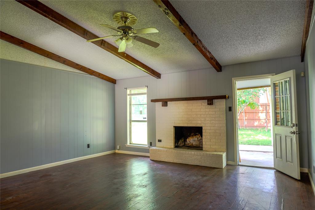 300 Coury Road Everman, TX 76140 - Photo 4 of 29 an empty room with fireplace wooden floor and windows