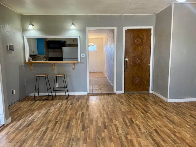an empty room with wooden floor fan and windows