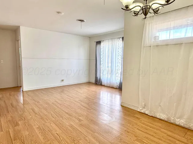 a view of an empty room with wooden floor and a ceiling fan