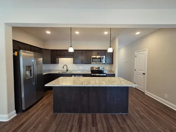 a large kitchen with a center island wooden floor stainless steel appliances and a window