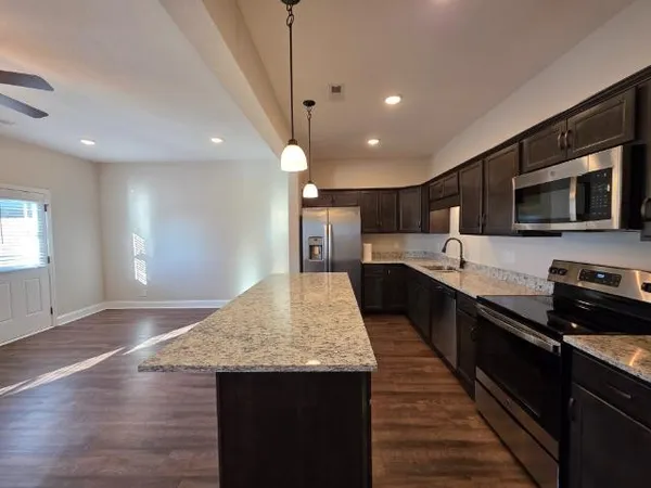 a large kitchen with stainless steel appliances kitchen island granite countertop a large counter top and wooden floors