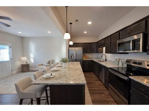 a kitchen with stainless steel appliances kitchen island granite countertop a sink dishwasher stove and microwave with wooden floor