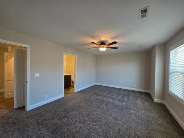 a view of an empty room with window and chandelier fan