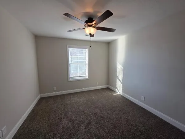 an empty room with ceiling fan and window