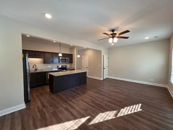 a large kitchen with kitchen island a sink dishwasher a stove and a refrigerator with wooden floor