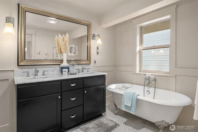 a bathroom with a tub a double vanity sink a toilet and mirror