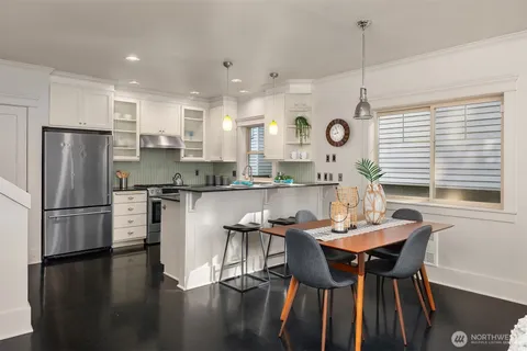 a kitchen with stainless steel appliances granite countertop a dining table chairs a sink a stove and a refrigerator