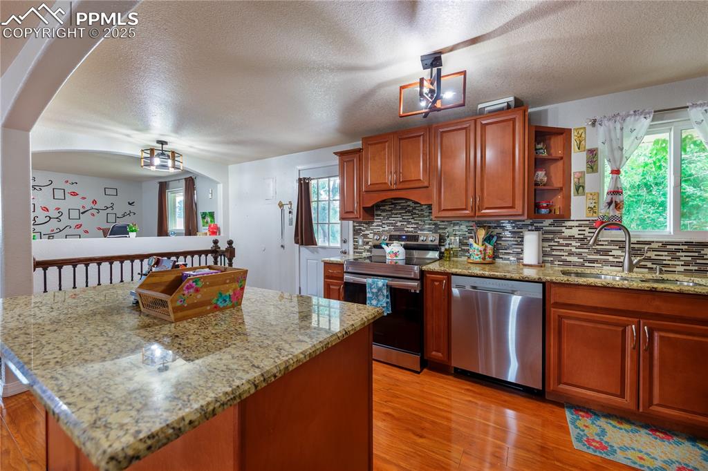 2205 Airport Road Colorado Springs, CO 80910 - Photo 10 of 40 a kitchen with stainless steel appliances granite countertop a sink dishwasher stove top oven and cabinets with wooden floor