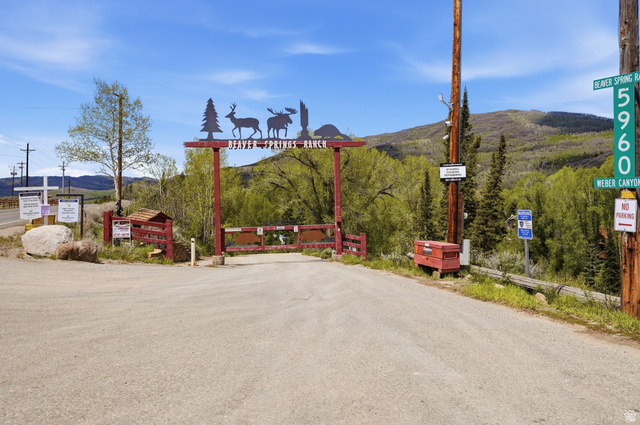 6 Beaver Springs Rancheros Oakley, UT 84055 - Photo 68 of 68 Gated entrance featuring a decorative Beaver Springs Ranch sign, mountain backdrop, and wooded surroundings