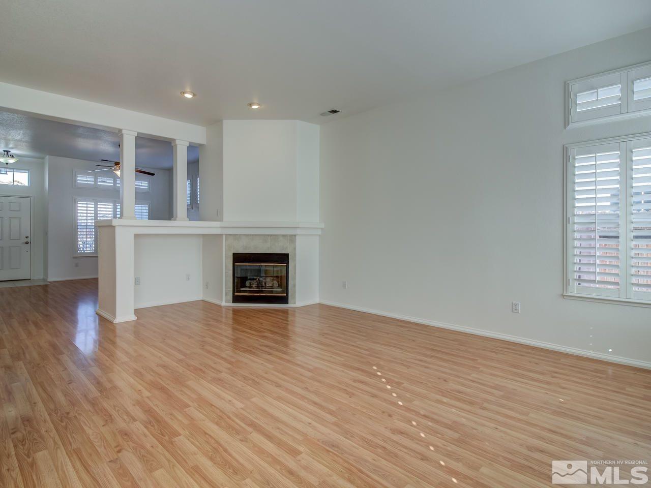 9350 Oakley Court Reno, NV 89521 - Photo 4 of 19 an empty room with wooden floor fireplace and windows