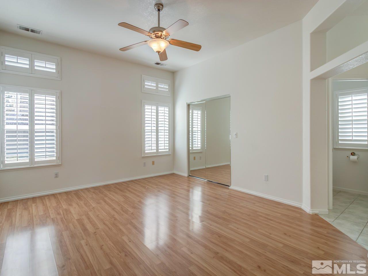 9350 Oakley Court Reno, NV 89521 - Photo 9 of 19 an empty room with wooden floor chandelier fan and windows
