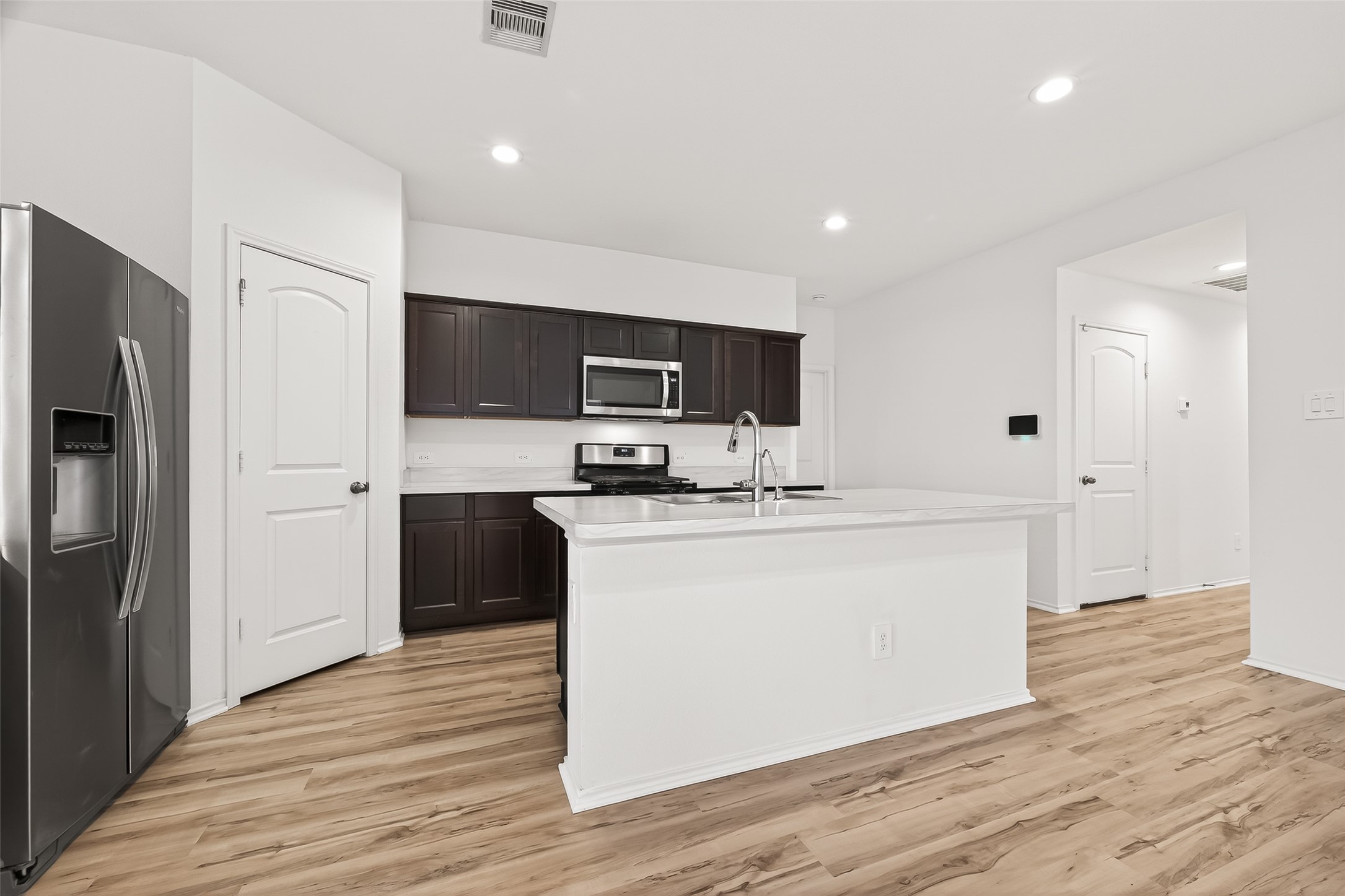 21522 Violet Ridge Road Katy, TX 77449 - Photo 17 of 39 Spacious white island with a sink, open layout, and wood-style flooring continues to create a bright, welcoming space ideal for cooking and entertaining.